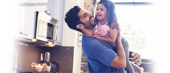 A smiling man lifting his daughter into his arms